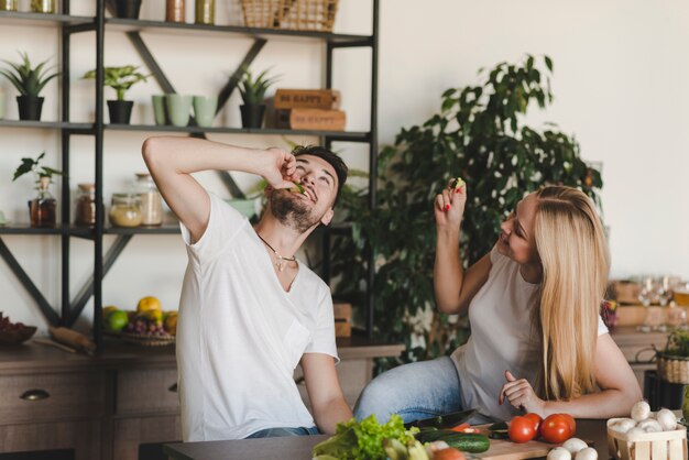 Paare, die in der Küche isst Gurkenscheibe sitzen