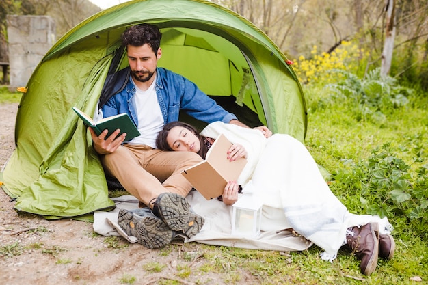 Paare, die nahe Zelt stillstehen und lesen