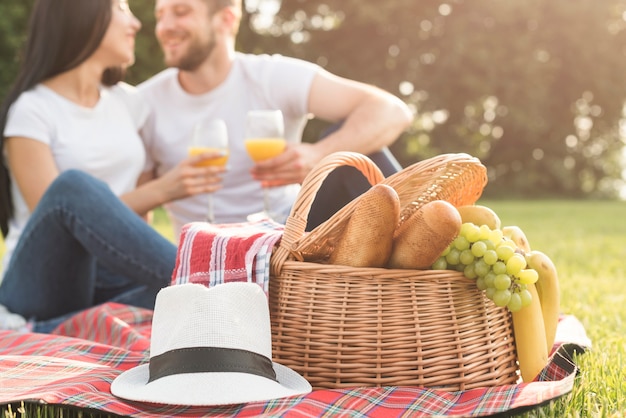 Paare, die Orangensaft auf Picknickdecke essen
