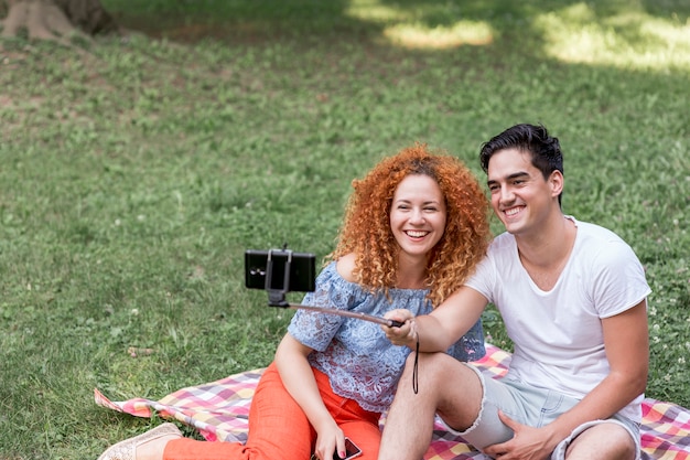 Kostenloses Foto paare, die selfies mit intelligentem telefon am picknicktermin nehmen