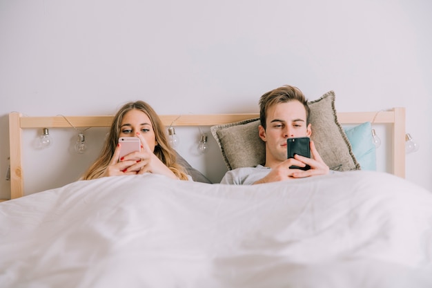 Paare, die Smartphones im Bett verwenden