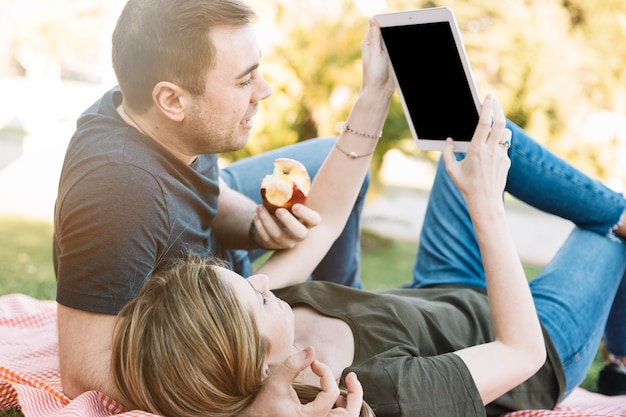 Paare, die Tablette auf Picknick durchstöbern