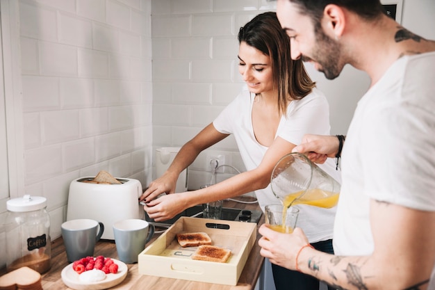 Paare, die Toast machen und Saft gießen