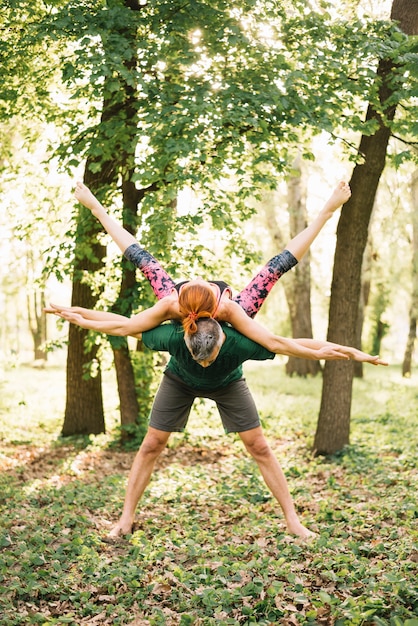 Paare, die übendes Yoga der Balance im Park tun