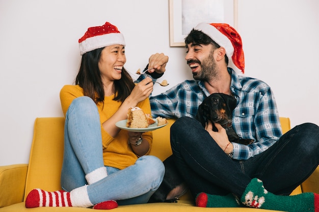 Paare, die Weihnachten auf Couch mit Hund feiern
