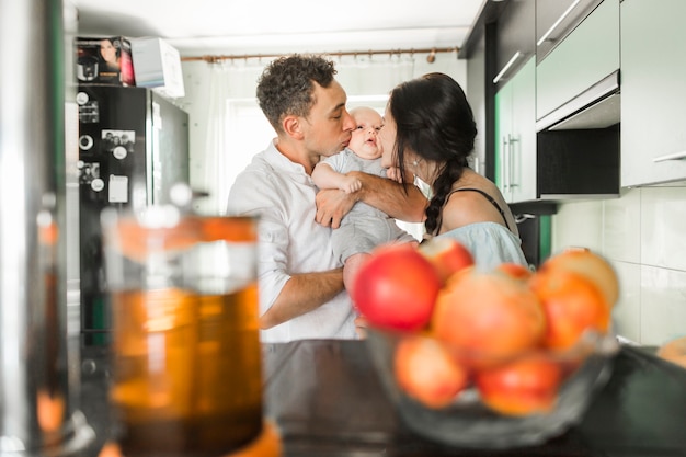 Paare, die zu ihrem Baby in der Küche küssen