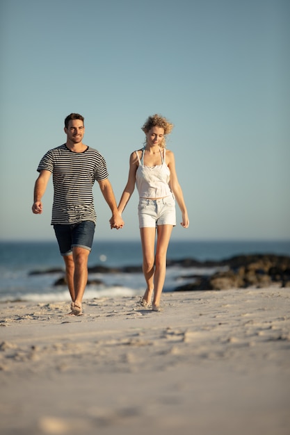 Paare, die zusammen Hand in Hand auf den Strand gehen