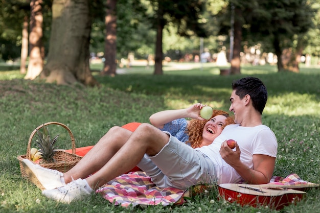 Paare, die zusammen Äpfel im Park essen