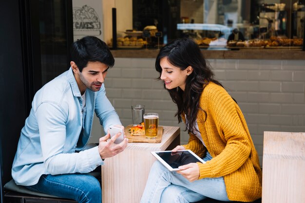 Paare im Café, das Smartphoneschirm betrachtet