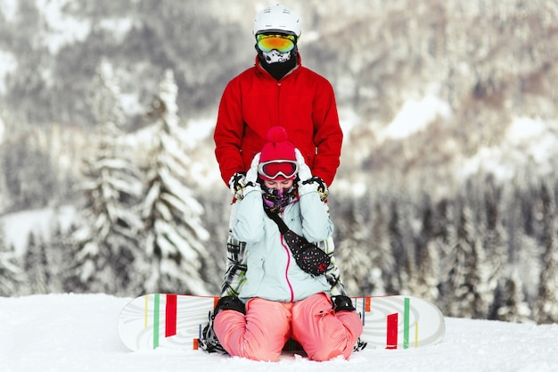 Paare in den bunten Skianzügen werfen auf dem Hügel irgendwo in den Bergen auf