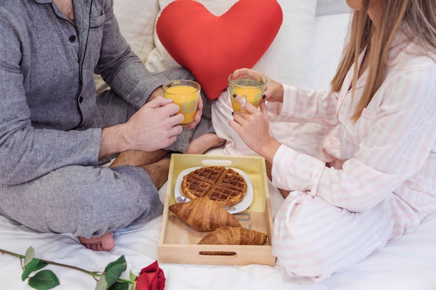 Paare in den Pyjamas, die Saft auf Bett trinken