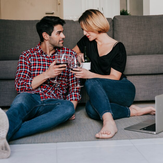 Paare mit dem Wein, der an der Couch sitzt