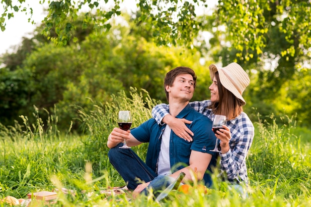 Paare mit den Weingläsern, die in der Natur umarmen