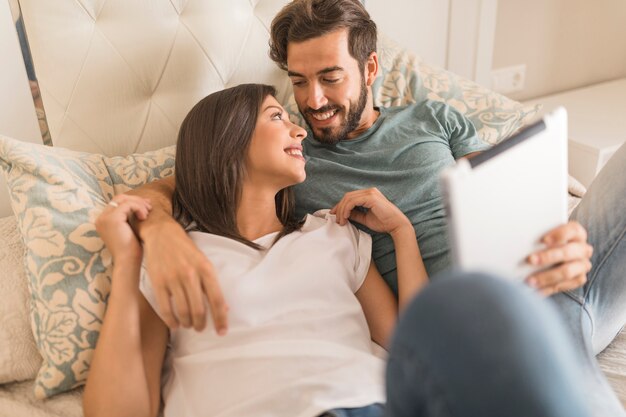 Paare mit der Tablette, die auf Bett liegt