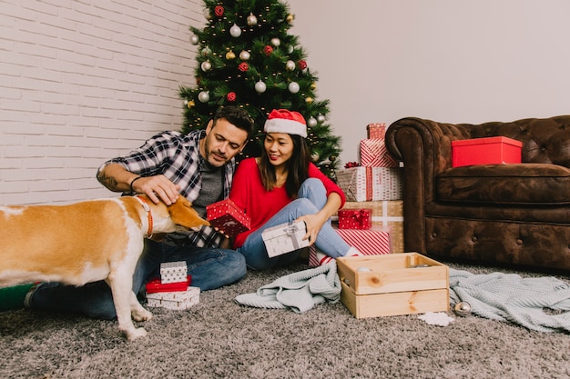 Paare zu Hause, die Weihnachten mit Hund feiern