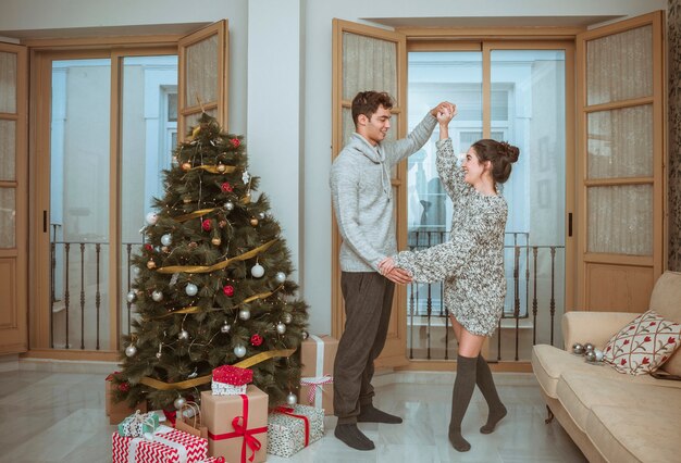 Paartanzenholdinghände nähern sich Weihnachtsbaum