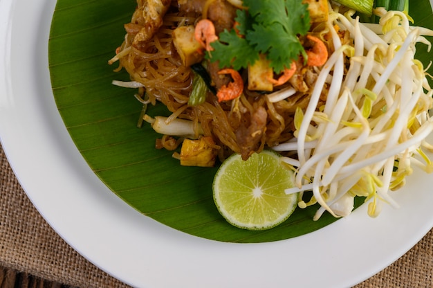 Pad Thai in einem weißen Teller mit Zitrone auf einem Holztisch