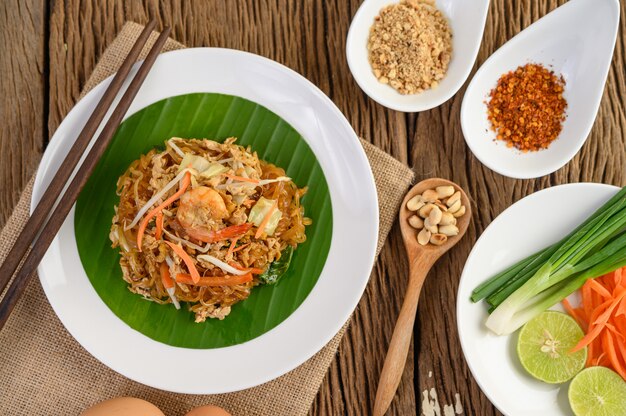 Padthai-Garnelen in einer schwarzen Schüssel mit Eiern, Frühlingszwiebeln und Gewürzen auf Holztisch.