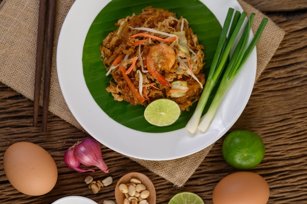 Padthai-garnelen in einer weißen schale mit limette und eiern auf holztisch.