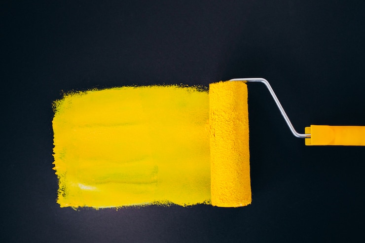 Kostenlose Foto paintroller für reparaturen, isoliert auf schwarzem hintergrund in gelben farben