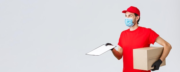Paket- und Päckchenzustellung covid19 Zustellungsaufträge Profil eines freundlichen Kuriers in roter Uniform mit Gesichtsmaske und Handschuhen Bringen Sie eine Aufbewahrungsbox mit und geben Sie dem Kunden ein Formular zum Unterschreiben