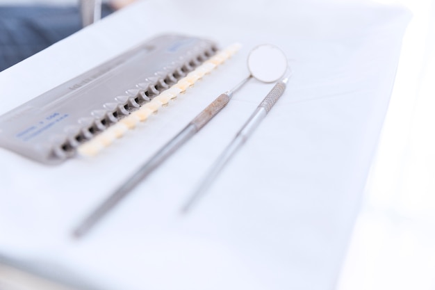 Palette der Zähne schattet mit zahnmedizinischem Spiegel und Sonde auf Schreibtisch