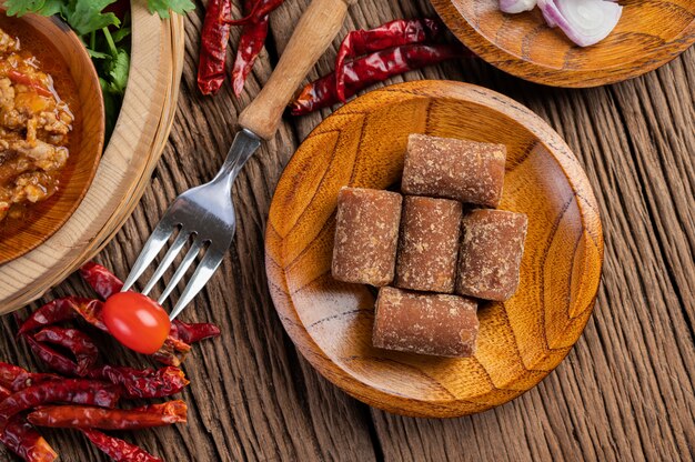 Palmzucker, rote Zwiebeln, getrocknete Paprika, Tomaten, Gurken, lange Bohnen und Salat in einer Schüssel.