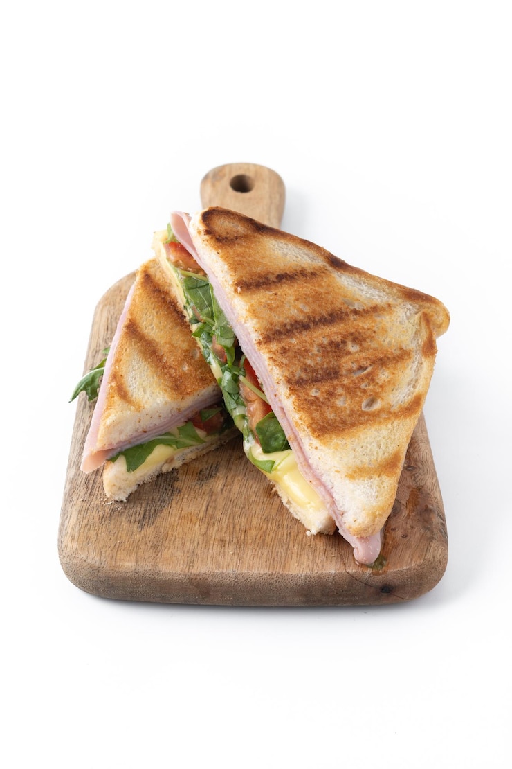 Kostenlose Foto panini-sandwich mit schinken, käse, tomaten und arugula auf weißem hintergrund