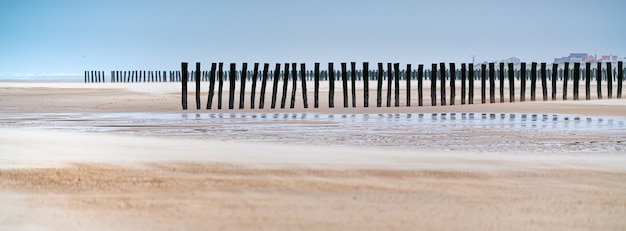 Panorama der vertikalen Holzbretter im Sand eines unfertigen Holzdocks am Strand in Frankreich