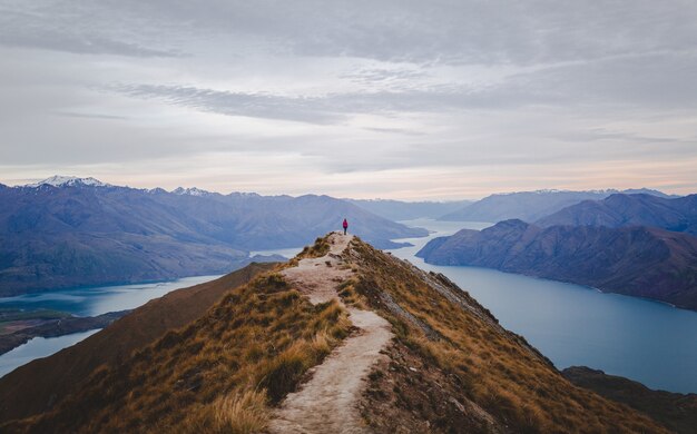 Panoramablick auf den Roys Peak in Neuseeland mit niedrigen Bergen in der Ferne unter Wolkenlandschaft