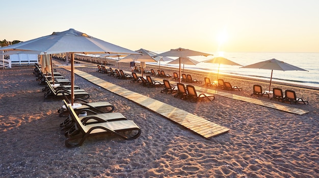 Panoramablick auf den Sandstrand am Strand mit Sonnenliegen und Sonnenschirmen gegen Meer und Berge. Hotel. Resort. Tekirova-Kemer. Truthahn