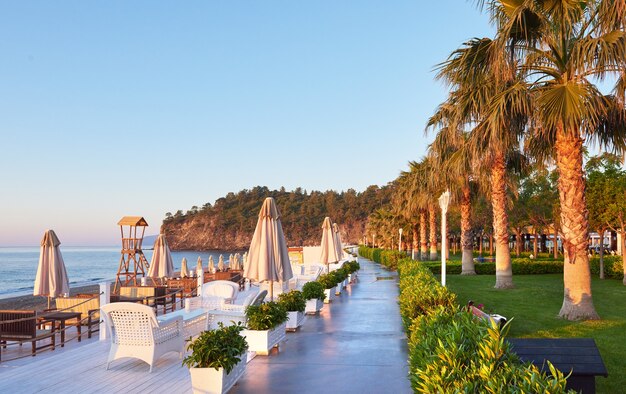 Panoramablick auf privaten Sandstrand mit Sonnenliegen und Parasokamy das Meer und die Berge. Resort.