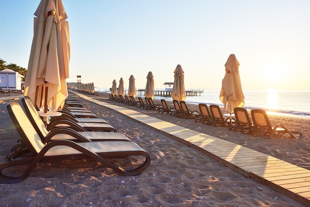 Panoramablick auf privaten Sandstrand mit Sonnenliegen und Parasokamy das Meer und die Berge. Resort.