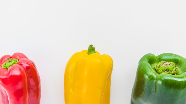 Panoramablick auf Rot; gelbe und grüne Paprika auf weißer Oberfläche