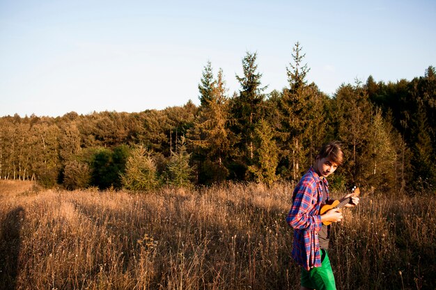 Panoramablick des Waldes und des Mannes, die Ukulele spielen