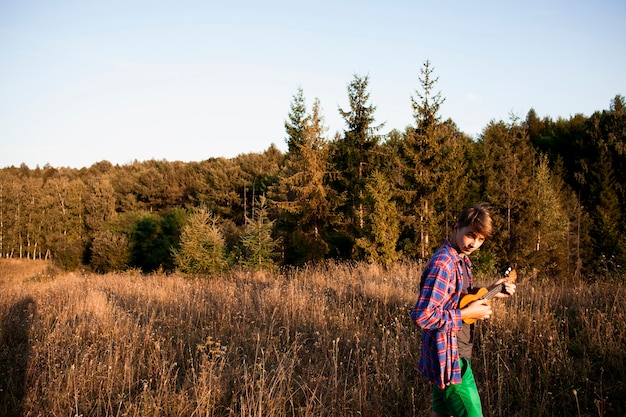 Panoramablick des Waldes und des Mannes, die Ukulele spielen