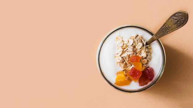 Panoramablick von Sauerrahmjoghurt mit den Hafern und Früchten, die im Glas übersteigen