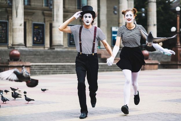Pantomimepaare, die auf Stadtpflasterung laufen