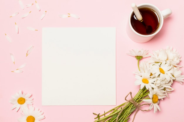 Papier in der Nähe von Blumen und Tasse Getränk