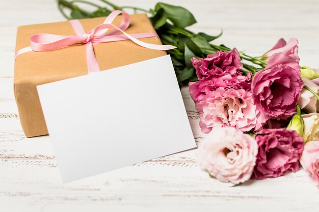 Papier in der Nähe von Geschenkbox und Blumen