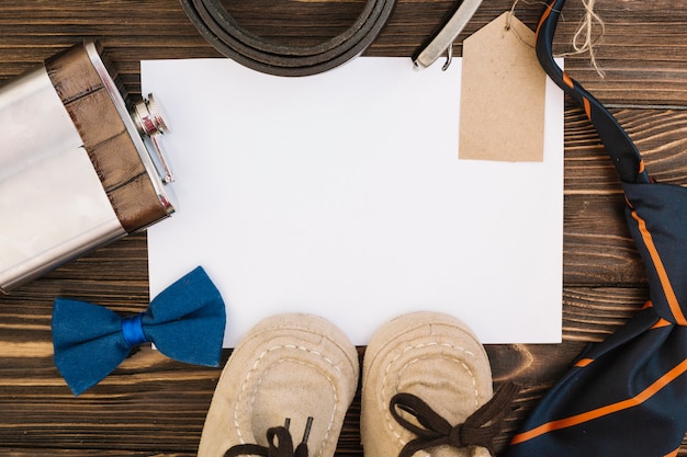 Papier in der Nähe von männlichen Accessoires und Kinderschuhen