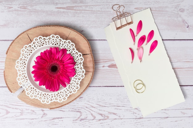 Papiere mit Blumenblättern und Ringen in der Nähe von Blumen auf Holz Runde