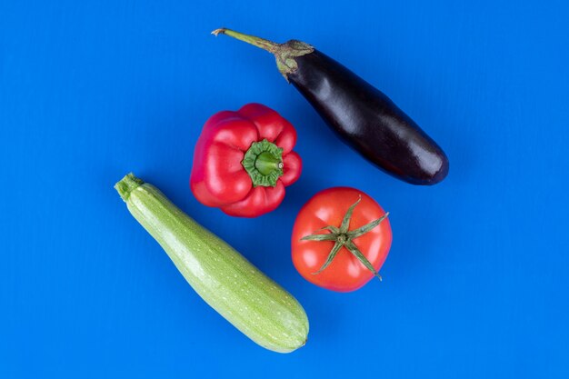 Paprika, Tomaten, Auberginen und Zucchini auf blauem Tisch.