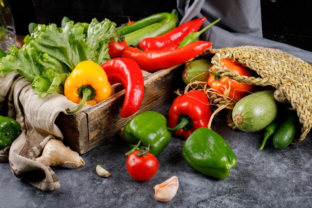 Paprika und Grün im rustikalen Korb und in einem Holztablett.