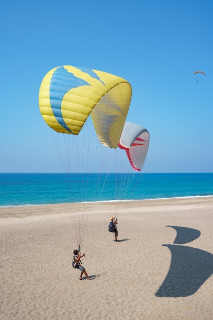 Kostenloses Foto paraglider tandem fliegt über die küste mit blauem wasser und himmel auf horison. ansicht des gleitschirms und der blauen lagune in der türkei.