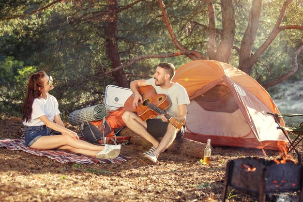 Party, Camping der Männer- und Frauengruppe am Wald. Sie entspannen sich und singen ein Lied gegen grünes Gras. Konzept