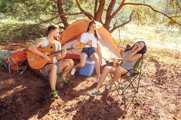 Party, Camping der Männer- und Frauengruppe am Wald. Sie entspannen sich und singen ein Lied