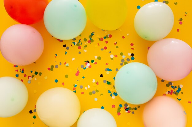 Party mit Konfetti und Luftballons auf gelb