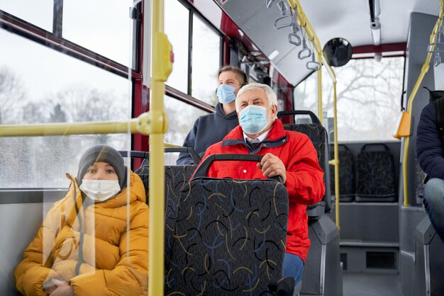 Passagiere sitzen im Bus und tragen medizinische Masken, die vor der globalen Pandemie schützen