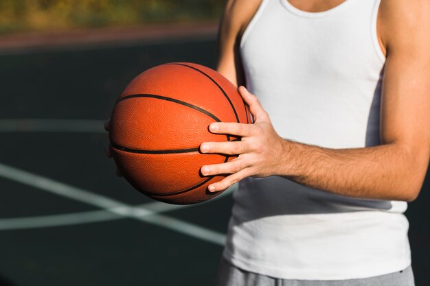 Passender nicht erkennbarer Athlet, der Basketball hält